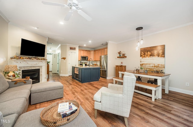 living area featuring ornamental molding, baseboards, ceiling fan, light wood-type flooring, and recessed lighting