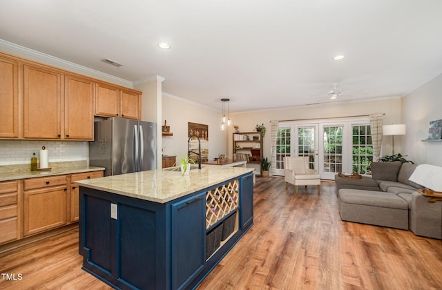 kitchen featuring freestanding refrigerator, open floor plan, crown molding, a sink, and ceiling fan