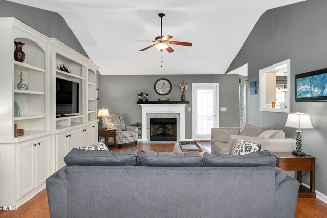 living room featuring vaulted ceiling, ceiling fan, wood finished floors, a high end fireplace, and baseboards