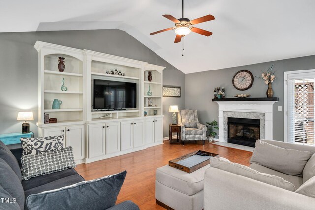 living room with a ceiling fan, vaulted ceiling, light wood-style flooring, and a premium fireplace