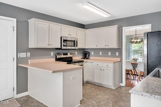 kitchen featuring stainless steel appliances, white cabinets, light countertops, and a chandelier