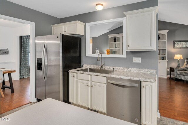 kitchen featuring stainless steel appliances, a sink, dark wood-style floors, white cabinetry, and vaulted ceiling