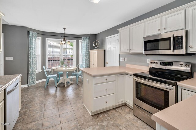 kitchen with stainless steel appliances, light countertops, white cabinetry, baseboards, and hanging light fixtures