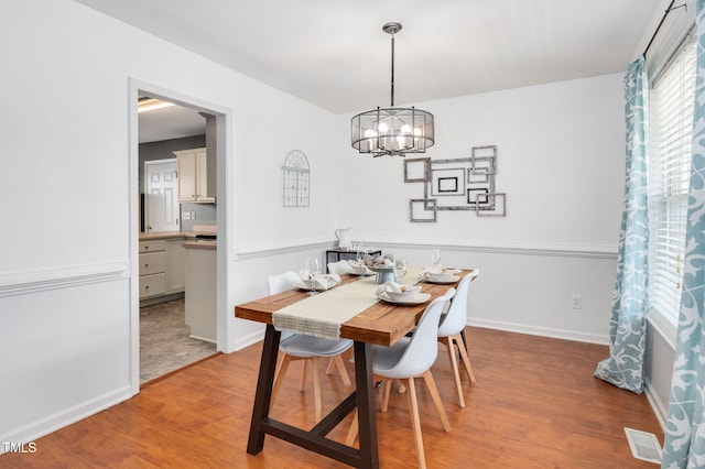 dining area with light wood-type flooring, a chandelier, and baseboards