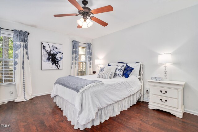 bedroom with multiple windows, dark wood-type flooring, and baseboards