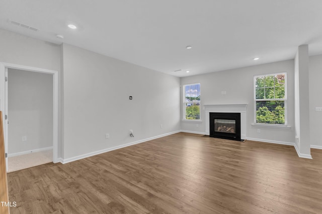 2100 Curry Meadow Way, Durham, NC 27703 - unfurnished living room featuring plenty of natural light, wood finished floors, a fireplace with flush hearth, and recessed lighting