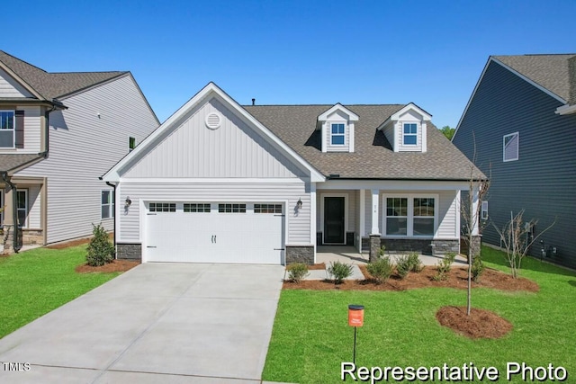 view of front facade with board and batten siding, a front yard, a garage, concrete driveway, and stone siding