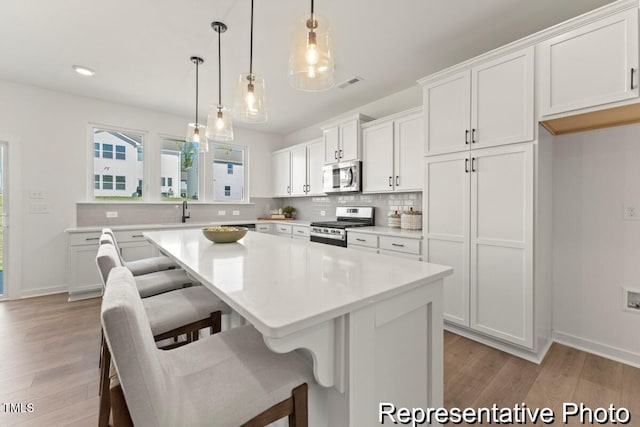 kitchen with stainless steel appliances, decorative backsplash, visible vents, and white cabinets