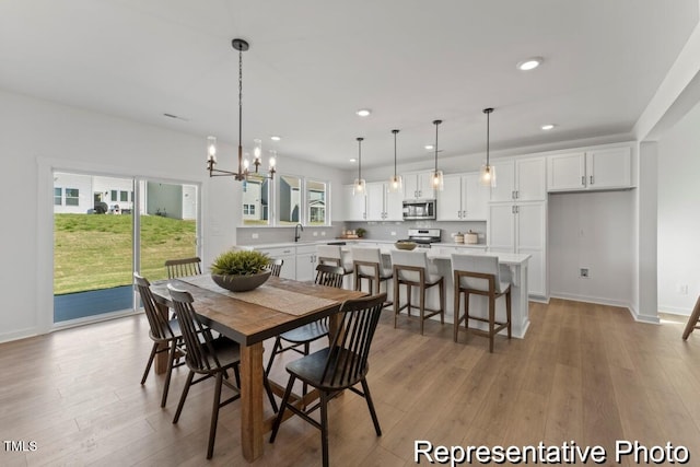 dining area with an inviting chandelier, light wood-style flooring, baseboards, and recessed lighting