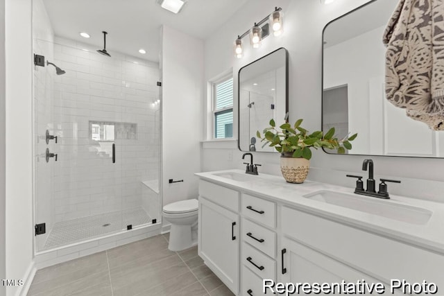 bathroom featuring a stall shower, toilet, a sink, and double vanity