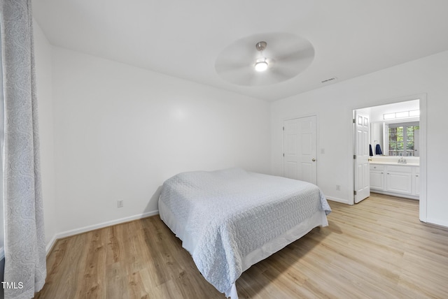 bedroom with light wood finished floors, baseboards, ceiling fan, and ensuite bathroom