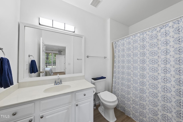 ensuite bathroom with wood finished floors, vanity, toilet, and curtained shower