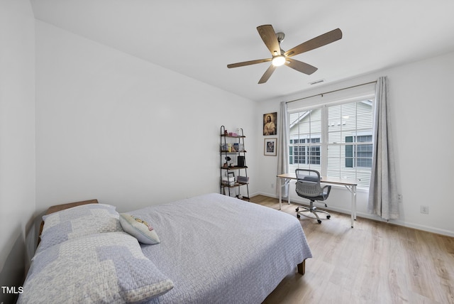 bedroom with light wood-style floors, ceiling fan, baseboards, and a desk