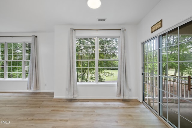 unfurnished dining area with healthy amount of natural light, wood finished floors, and baseboards