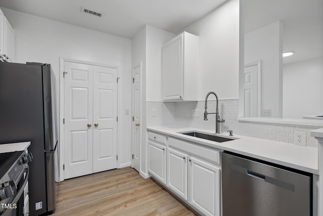 kitchen with stainless steel appliances, a sink, and white cabinetry