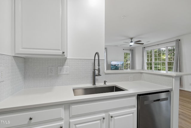 kitchen featuring dishwasher, a sink, a ceiling fan, white cabinets, and backsplash