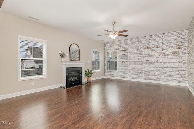 unfurnished living room featuring a ceiling fan, baseboards, a glass covered fireplace, visible vents, and wood finished floors
