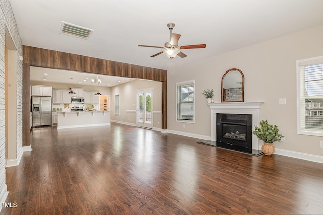 unfurnished living room with plenty of natural light, visible vents, ceiling fan, and dark wood-type flooring