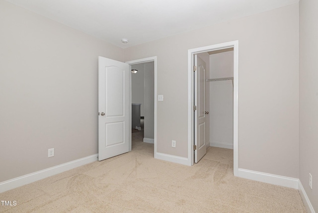 unfurnished bedroom with a walk in closet, carpet floors, baseboards, and a closet