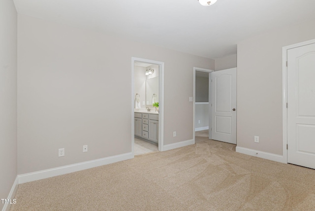unfurnished bedroom featuring ensuite bath, light colored carpet, and baseboards