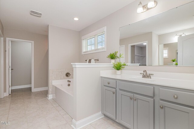 full bath with a garden tub, baseboards, and vanity