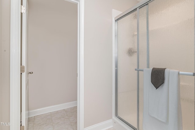 full bathroom featuring a stall shower and baseboards