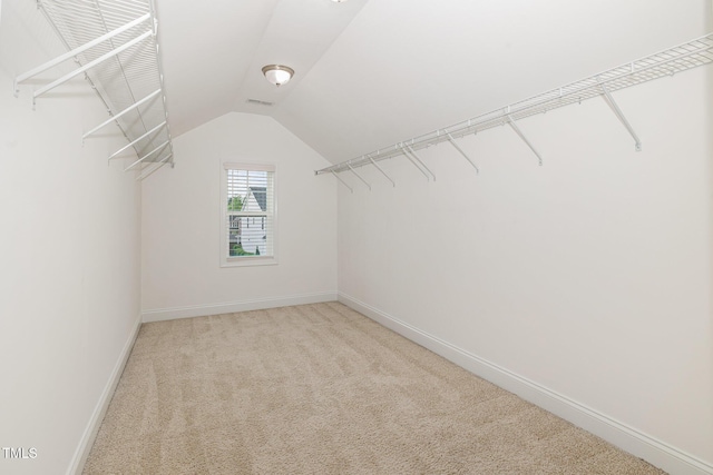spacious closet with visible vents, carpet, and vaulted ceiling
