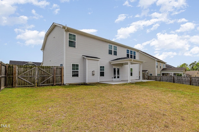 rear view of property with a yard, a patio, a fenced backyard, and a gate