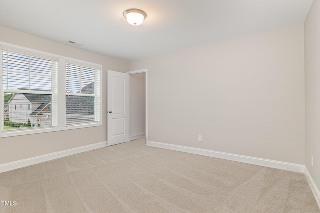 unfurnished room with light colored carpet, baseboards, and visible vents