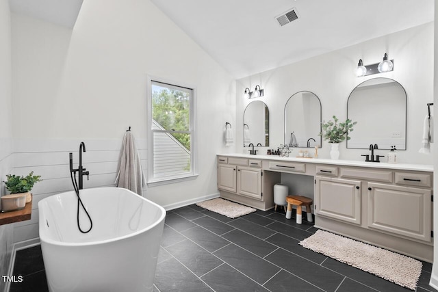 bathroom with lofted ceiling, double vanity, a freestanding tub, and baseboards
