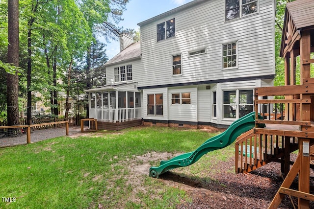 back of house with a playground, a sunroom, and a chimney