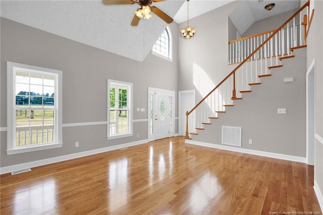 unfurnished living room with visible vents, wood finished floors, stairway, and high vaulted ceiling