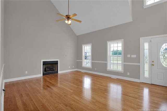 unfurnished living room featuring wood finished floors, a ceiling fan, a fireplace, and high vaulted ceiling