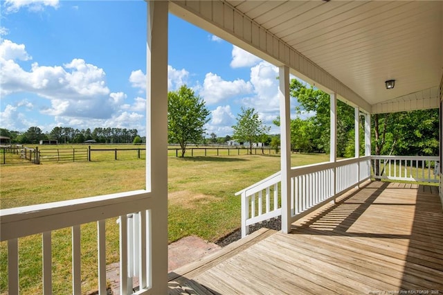 wooden terrace featuring a lawn, a rural view, and fence