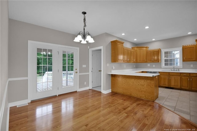 kitchen with brown cabinets, a notable chandelier, light countertops, and a peninsula