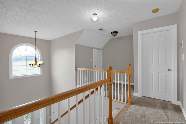 hall featuring carpet, an upstairs landing, a textured ceiling, baseboards, and a chandelier