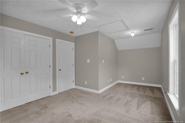 unfurnished bedroom featuring a textured ceiling, baseboards, attic access, and carpet floors