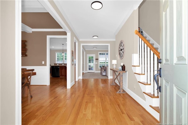 entrance foyer featuring stairs, ornamental molding, light wood-style flooring, and wainscoting