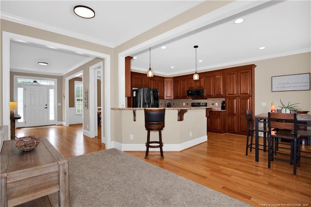 kitchen with black appliances, a breakfast bar area, light wood-style floors, a peninsula, and backsplash