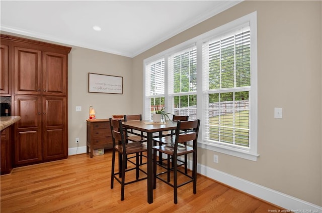 dining area featuring light wood-style floors, crown molding, and baseboards