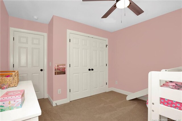 bedroom with light carpet, baseboards, a closet, and ceiling fan