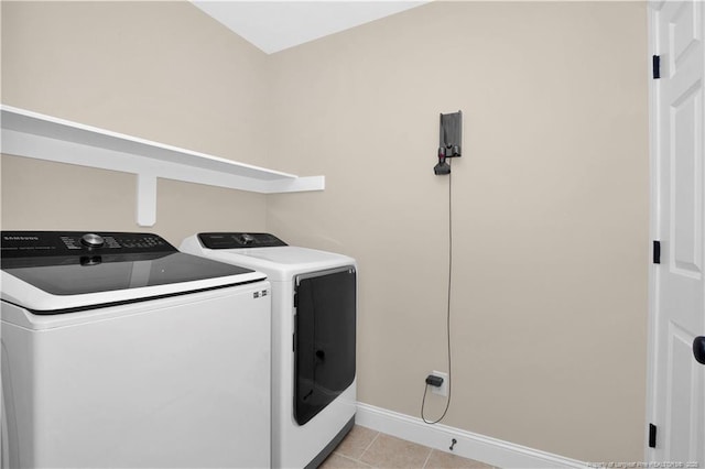 laundry area with washing machine and clothes dryer, baseboards, and light tile patterned floors