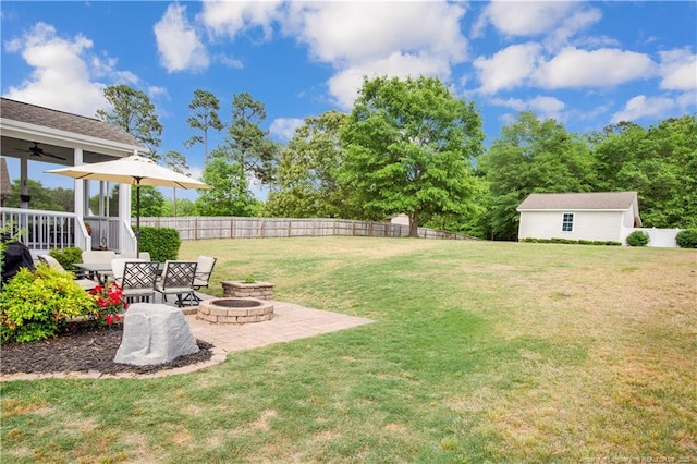 view of yard featuring a fire pit, ceiling fan, an outdoor structure, and a patio