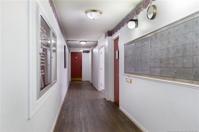 hallway with baseboards, dark wood-style flooring, and mail area