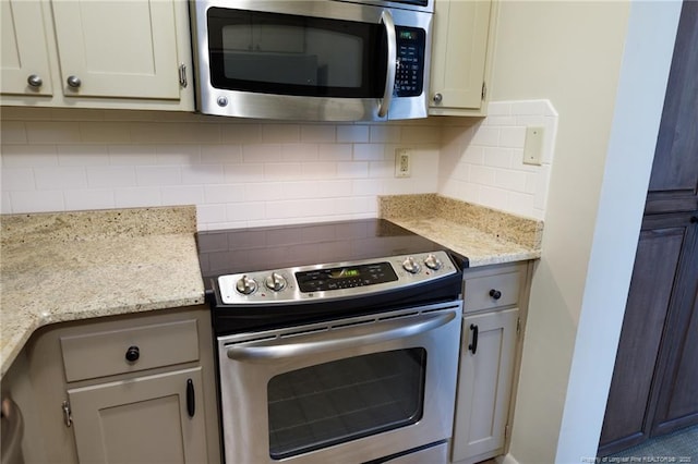 kitchen with appliances with stainless steel finishes, tasteful backsplash, and light stone countertops