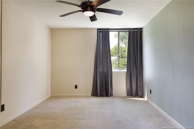 carpeted empty room with ceiling fan, a textured ceiling, and baseboards