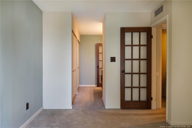hallway with carpet flooring, visible vents, and baseboards