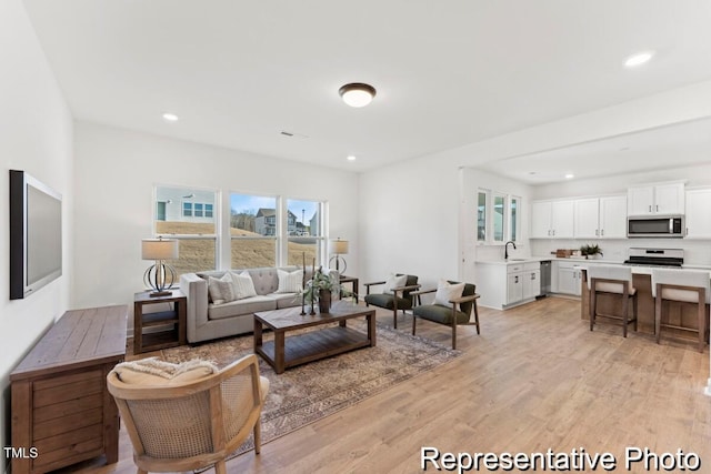 living room with light wood finished floors, recessed lighting, and plenty of natural light