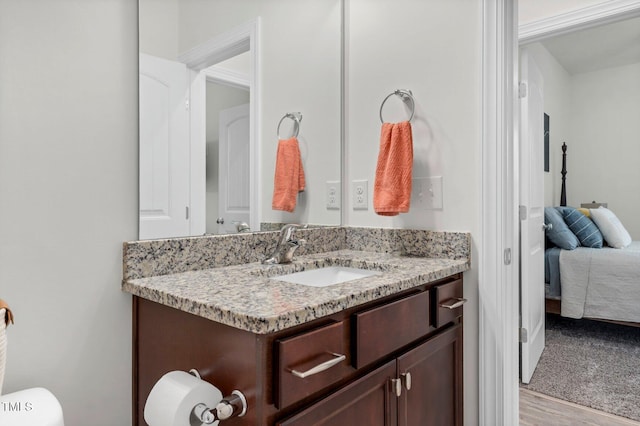 half bath with vanity, toilet, and wood finished floors