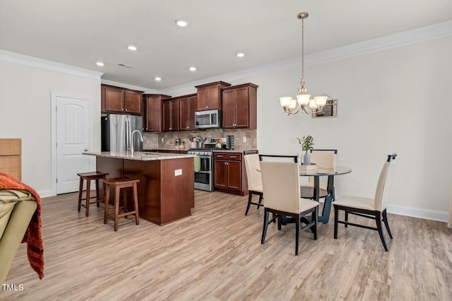 kitchen with stainless steel appliances, ornamental molding, a chandelier, decorative backsplash, and a breakfast bar